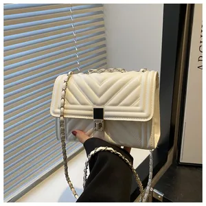 Close-up of white quilted leather texture with silver metal twist lock and chain strap
