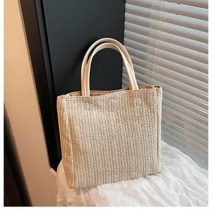Detail of herringbone woven texture and faux leather handle on summer straw tote bag