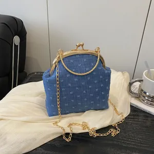 Borsa a mano retrò in denim con chiusura dorata e tracolla su sfondo bianco pulito