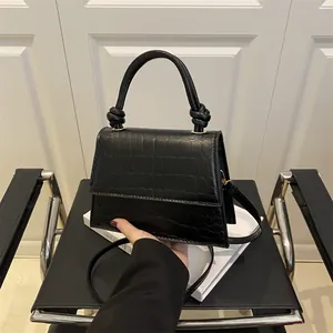 Sac à main noir motif crocodile avec poignée à nœud unique et finitions dorées