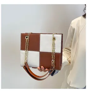 Detail of checkered shoulder bag featuring brown and white leather with gold chain strap