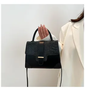 Détails d'un sac à main en similicuir noir avec motif crocodile et boucle dorée