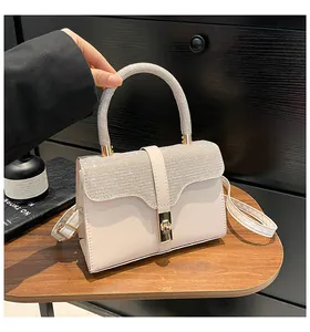Detailansicht der beigen Handtasche mit glitzerndem Strassgriff und goldenem Schloss