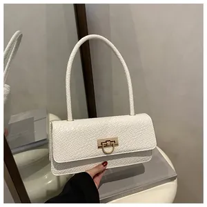 Detalle de bolso blanco con relieve de cocodrilo y cierre metálico dorado de herradura