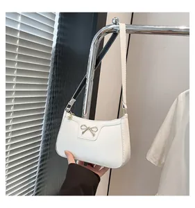 Close-up of the white PU leather baguette bag featuring a golden metal bow buckle