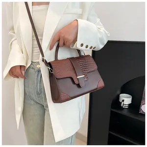 Sac à main vintage marron avec texture crocodile et bandoulière sur mannequin en blazer
