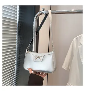 Close-up of shiny silver underarm bag with a delicate gold bow metallic detail