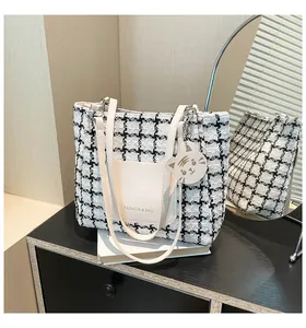 Detail of checkered canvas tote bag with fashion lettering and cute tiger charm accessory