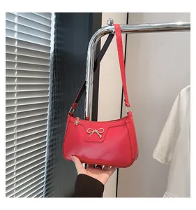 Close-up of red glossy baguette bag with silver bow accent and floral zipper detail