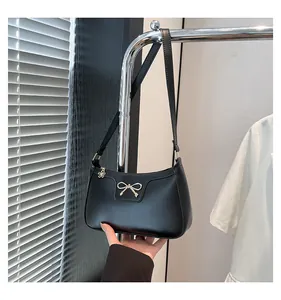 Detail of elegant black faux leather shoulder bag with golden bow and flower zipper