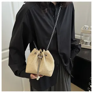 Detail of beige woven bucket bag featuring drawstring closure and pearl accents