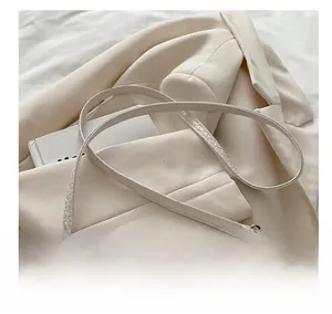 Detail showing the comfortable woven strap and gold metal buckle of the cream square bag