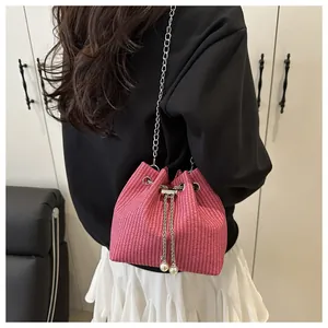 Detail of pink woven bucket bag with pearl drawstring charms and chain strap