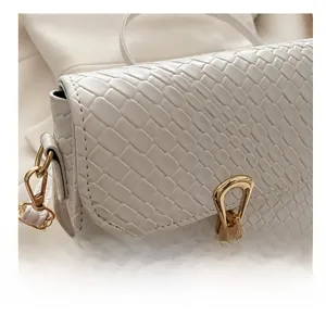 Close-up of white woven leather texture with gold metal buckle on a square handbag