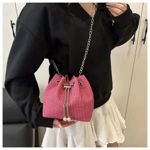 Detail of pink woven bucket bag with silver chain and decorative white pearl accents
