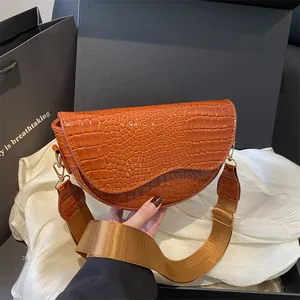 Brown crocodile embossed saddle bag with stylish wide woven strap and gold hardware
