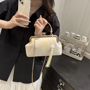 Close-up of vintage beige shell bag with floral embroidery and golden metal handle