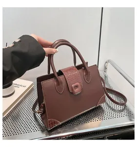 Dettagli borsa a tracolla in pelle marrone scuro con trama coccodrillo e manico in metallo
