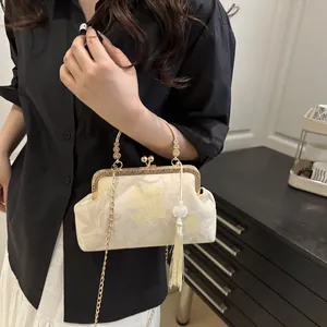 Detail of vintage beige shell bag with floral embroidery and golden metal ring handle