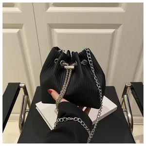 Close-up of textured black drawstring bucket bag with elegant silver chain strap