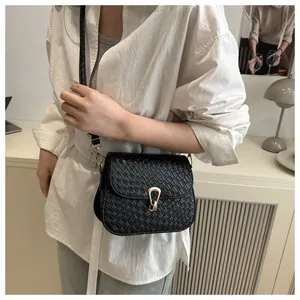 Detail shot of black crocodile embossed leather crossbody bag with golden buckle