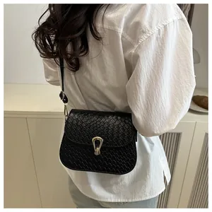 Detail of black snake-embossed small square bag featuring a gold horseshoe metal lock