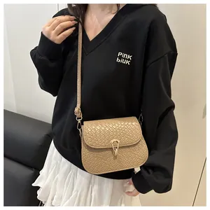 Detail of light brown woven texture and gold teardrop clasp on a stylish square crossbody bag