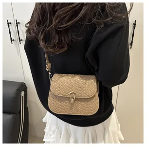 Detail of khaki crocodile pattern crossbody bag with a golden horseshoe buckle on model