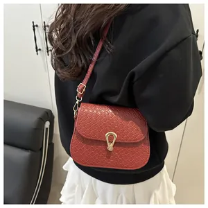 Detailed macro view of the woven texture and golden teardrop lock on red shoulder bag