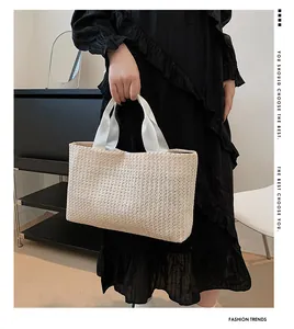 Detailed texture of beige woven straw tote bag with wide fabric handle on a model