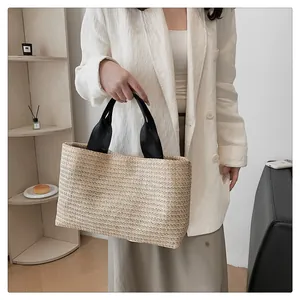 Close-up of woven straw tote bag texture and durable black fabric handles