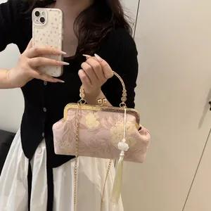 Close-up of pink floral cheongsam shell bag with gold clasp and silk tassel detail