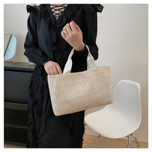Detail of hand-woven straw tote bag with white canvas handles and natural beige texture