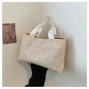 Detailed close-up of woven straw tote bag with fabric handles in a vacation setting