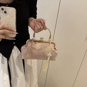 Macro detail of pink floral embroidery and vintage gold clasp on qipao shell bag