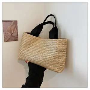 Macro detail of natural straw woven texture and black fabric handles on a tote bag