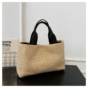 Detailed texture of beige woven straw tote bag with black fabric shoulder straps