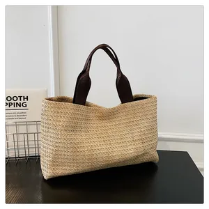 Detailed weave texture of the straw tote bag with brown fabric shoulder straps