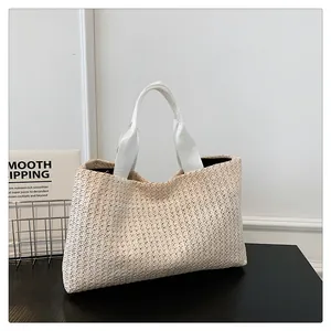 Close-up of a large woven straw tote bag featuring sturdy white fabric handles and a cream texture