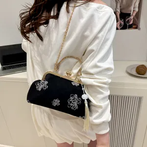 Detail of black satin qipao bag with white floral embroidery and vintage metal clasp