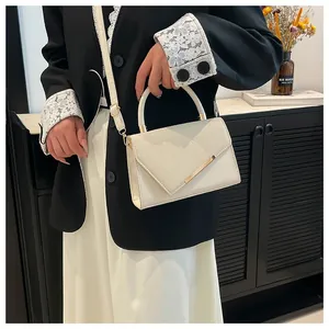 Petit sac à main beige minimaliste avec texture tressée et barre en métal doré