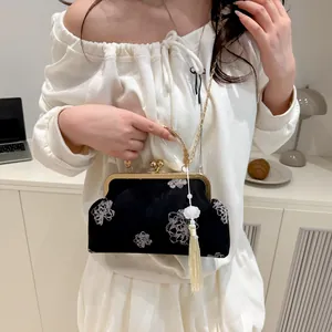 Close-up of black velvet cheongsam handbag with white flower embroidery and silk tassel
