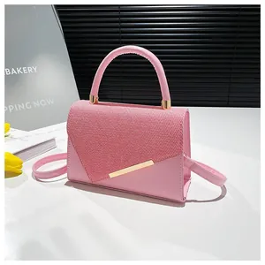 Sac à main en cuir rose et tissu avec barre métallique dorée et poignée chic