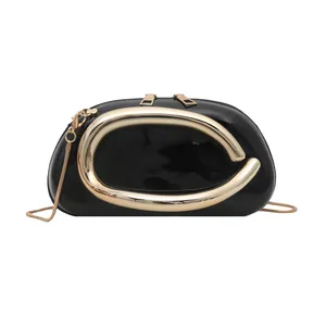Chic black patent leather round crossbody bag with a large golden metal handle