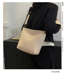 Détail du sac bandoulière en paille beige avec sangle à motifs géométriques sur modèle