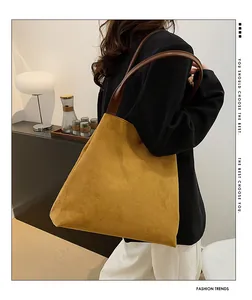 Detail of suede tote bag in mustard yellow with brown leather handles in a chic room