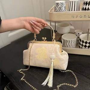 Detail of floral embroidery on a beige cheongsam bag with golden handle and long tassel