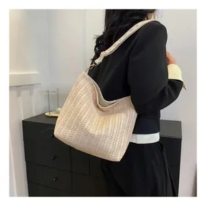 Détail du sac à bandoulière tressé beige avec crochets dorés et texture paille naturelle
