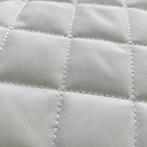 Close-up of classic diamond quilted texture and fine stitching on off-white crossbody bag