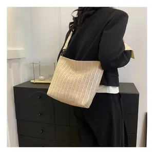 Détail du sac cabas en paille beige avec sangle à carreaux et mousquetons métalliques